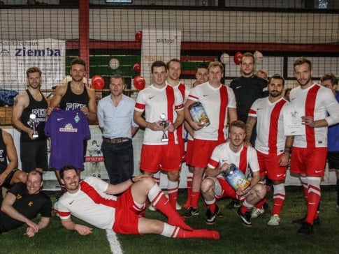 Eine Gruppe von Männern posiert für ein Foto. Sie tragen Sportkleidung und stehen auf einem Spielfeld Eine Gruppe von Männern posiert für ein Foto. Sie tragen Sportkleidung und stehen auf einem Spielfeld