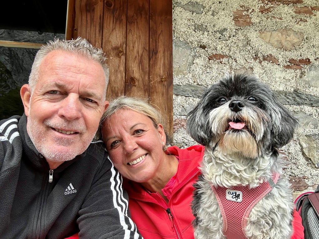 Ein Mann und eine Frau sind fröhlich vor einer Hauswand mit einem Hund Ein Mann und eine Frau sind fröhlich vor einer Hauswand mit einem Hund
