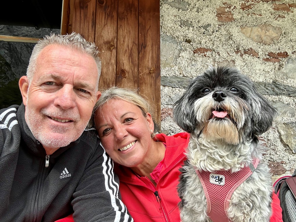Ein Mann und eine Frau sind fröhlich vor einer Hauswand mit einem Hund Ein Mann und eine Frau sind fröhlich vor einer Hauswand mit einem Hund