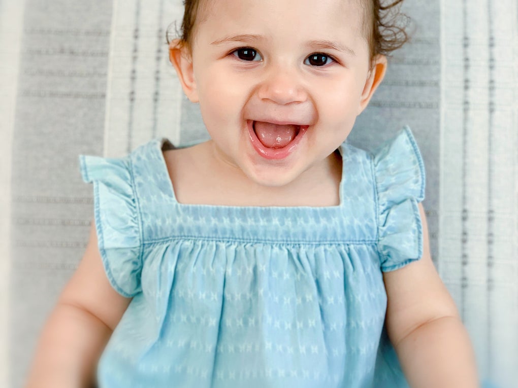 Die kleine Liya ist 18 Monate alt, sie trögt ein blaues Kleid und lächelt Die kleine Liya ist 18 Monate alt, sie trögt ein blaues Kleid und lächelt