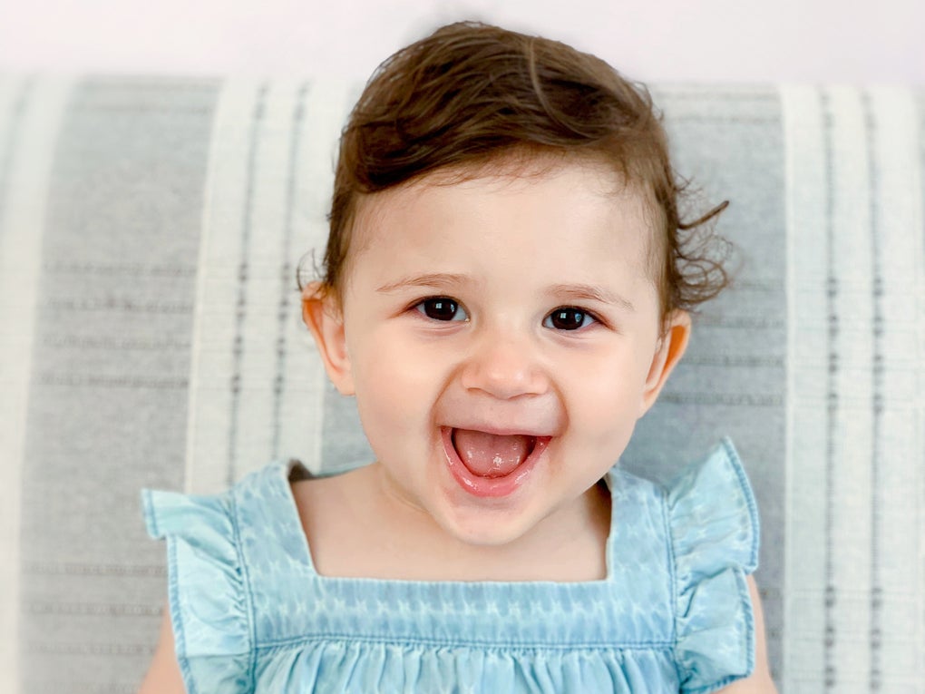 Die kleine Liya ist 18 Monate alt, sie trögt ein blaues Kleid und lächelt Die kleine Liya ist 18 Monate alt, sie trögt ein blaues Kleid und lächelt