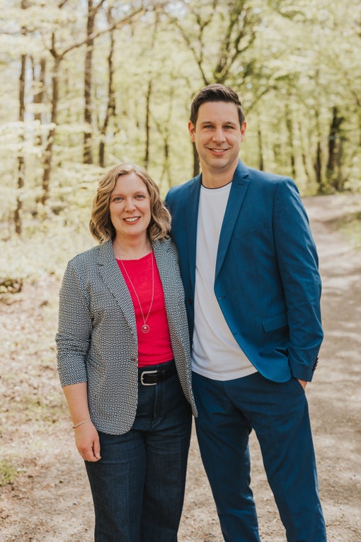 Christoph und seine Ehefrau stehen Arm in Arm in einem Wald und lächeln in die Kamera. Christoph und seine Ehefrau stehen Arm in Arm in einem Wald und lächeln in die Kamera.
