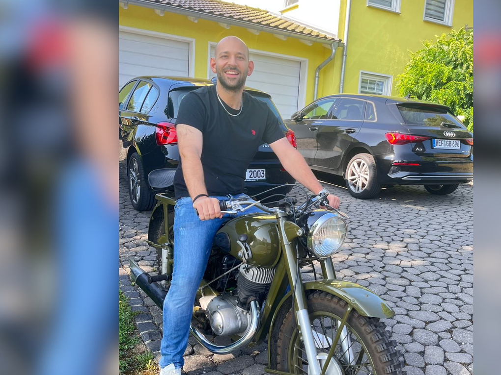 Ein Mann sitzt in T-Shirt und Jeans auf einem Motorrad. Ein Mann sitzt in T-Shirt und Jeans auf einem Motorrad.