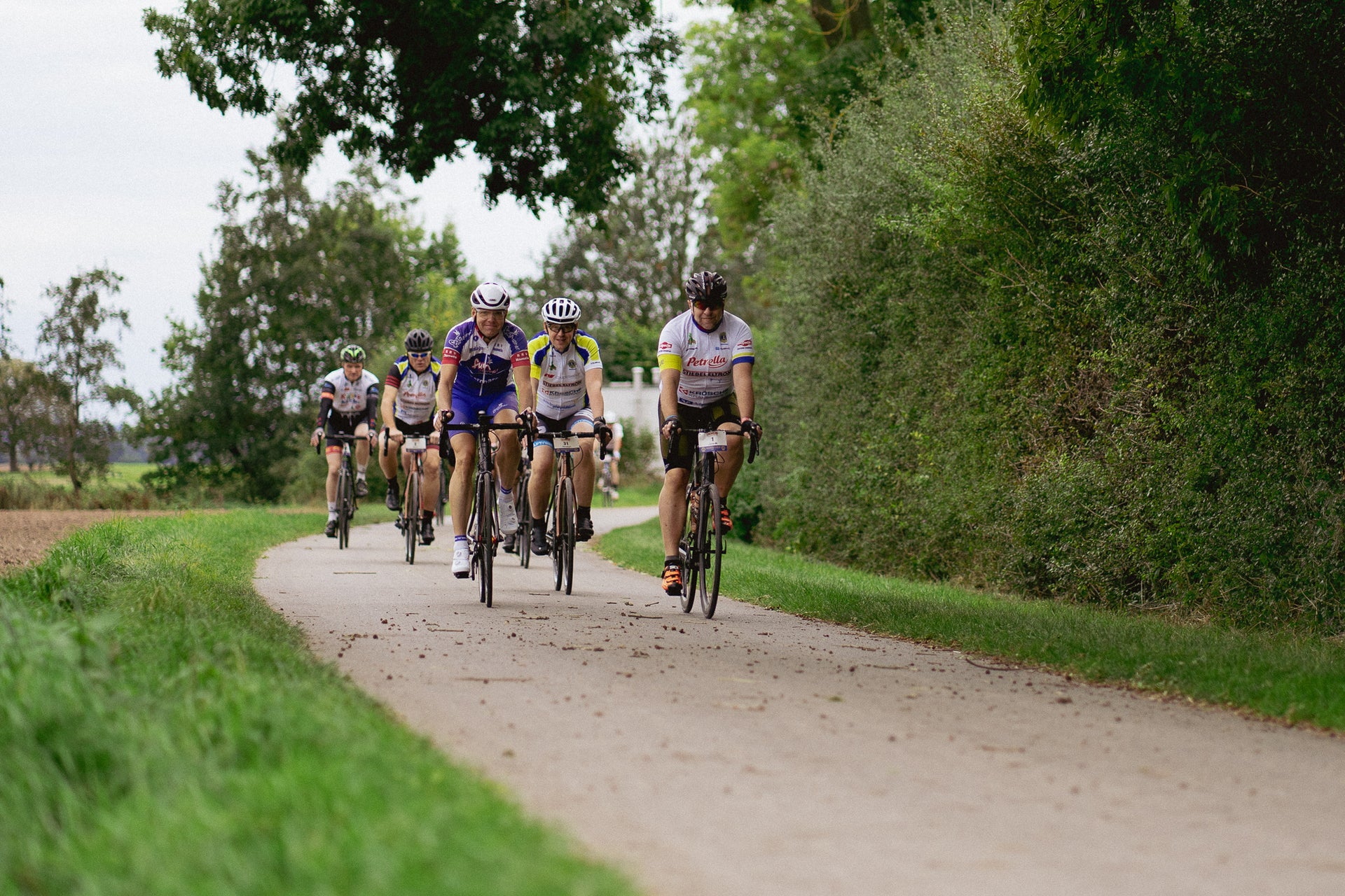 Eine Gruppe von Menschen, die auf einem Weg Fahrrad fahren Eine Gruppe von Menschen, die auf einem Weg Fahrrad fahren
