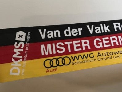 Nahaufnahme eine Deutschland Flagge mit dem Aufdruck Van der Valk Resort Linstow Mister Germany 2017. Link auf der Flagge ist ein DKMS Logo Nahaufnahme eine Deutschland Flagge mit dem Aufdruck Van der Valk Resort Linstow Mister Germany 2017. Link auf der Flagge ist ein DKMS Logo