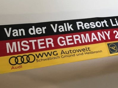 Nahaufnahme eine Deutschland Flagge mit dem Aufdruck Van der Valk Resort Linstow Mister Germany 2017. Link auf der Flagge ist ein DKMS Logo Nahaufnahme eine Deutschland Flagge mit dem Aufdruck Van der Valk Resort Linstow Mister Germany 2017. Link auf der Flagge ist ein DKMS Logo