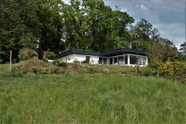 Ein Haus mit einem grasbewachsenen Hügel und Bäumen Ein Haus mit einem grasbewachsenen Hügel und Bäumen