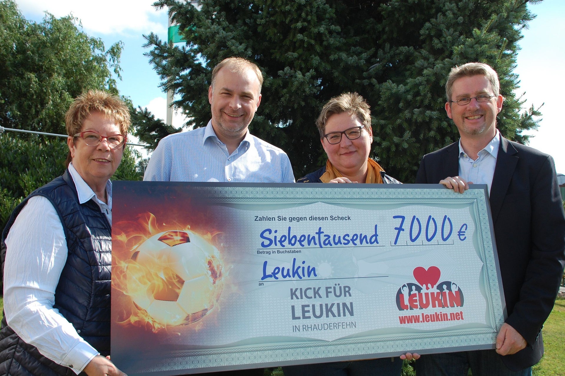 Vier Personen halten einen Check Vier Personen halten einen Check