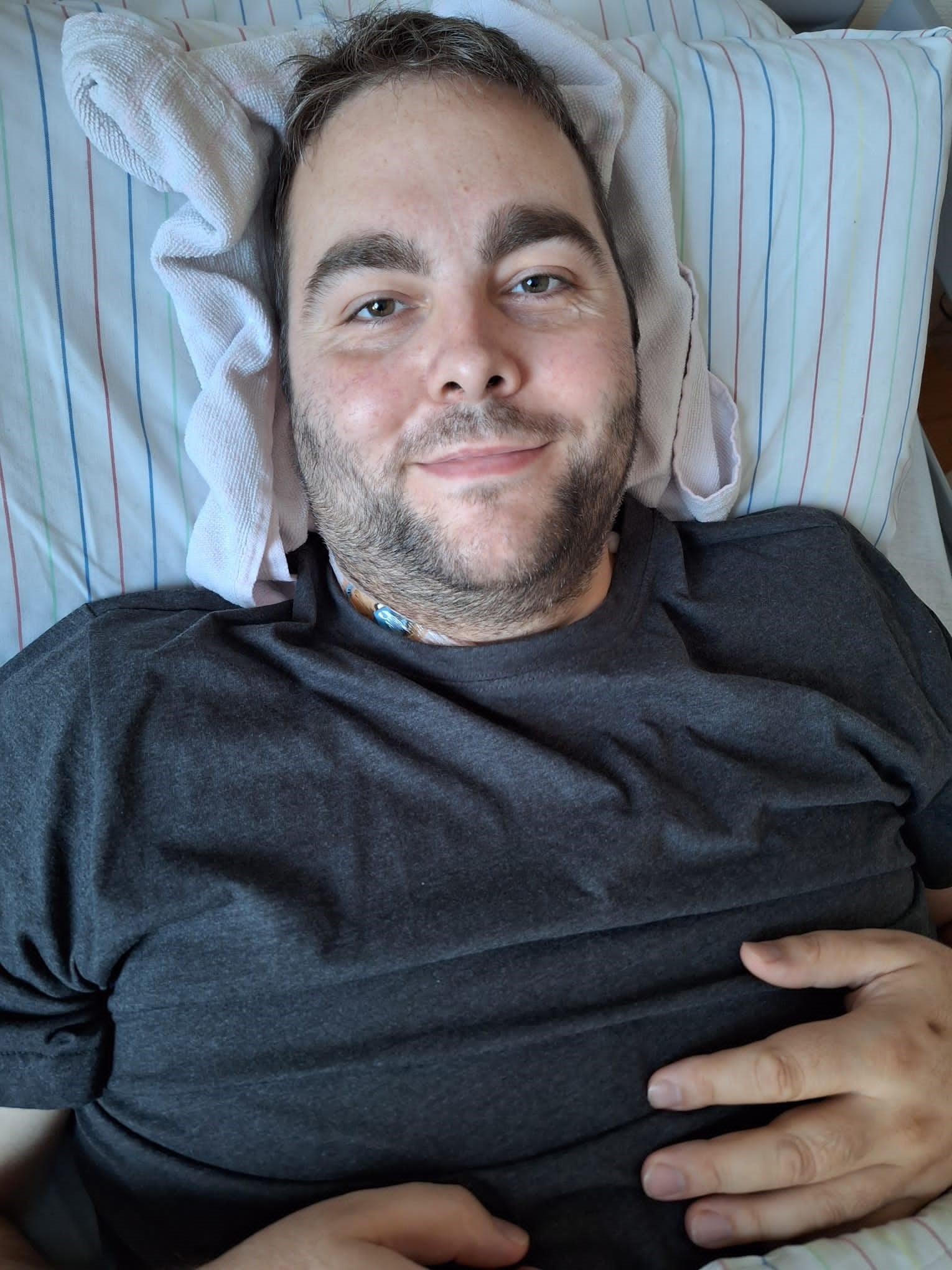 ein Mann liegt in einem Krankenhausbett und lächelt in die Kamera ein Mann liegt in einem Krankenhausbett und lächelt in die Kamera