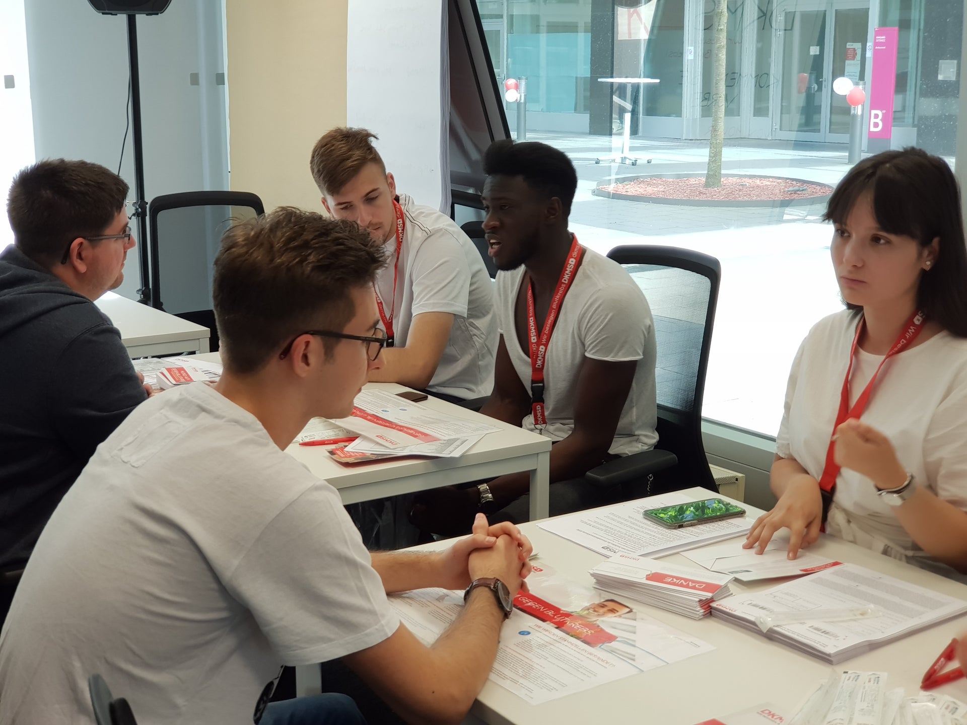 Eine Gruppe von Menschen, die sich gegenüber an Tischen sitzen Eine Gruppe von Menschen, die sich gegenüber an Tischen sitzen