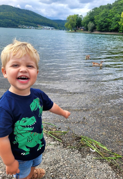 Der kleine David steht an einem See und lächelt in die Kamera Der kleine David steht an einem See und lächelt in die Kamera