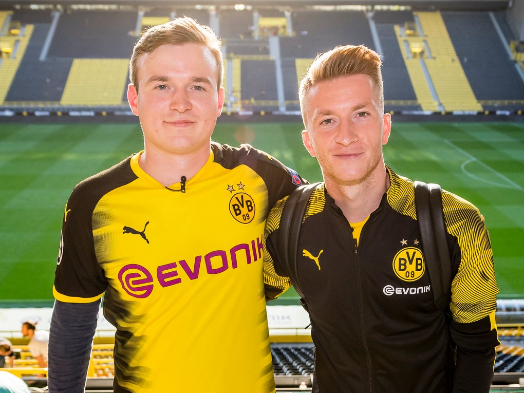 Ludwig Jolmes und Marco Reus, beide tragen BVB Merch und im Hintergrund sieht man das BVB Stadion Ludwig Jolmes und Marco Reus, beide tragen BVB Merch und im Hintergrund sieht man das BVB Stadion
