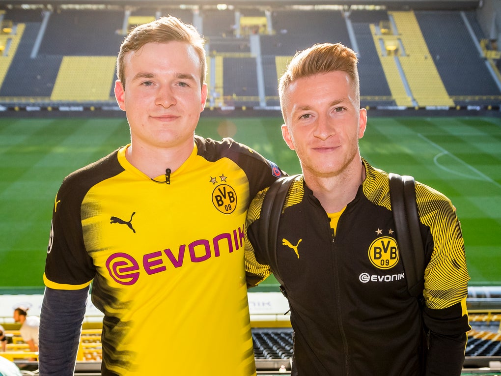 Ludwig Jolmes und Marco Reus, beide tragen BVB Merch und im Hintergrund sieht man das BVB Stadion Ludwig Jolmes und Marco Reus, beide tragen BVB Merch und im Hintergrund sieht man das BVB Stadion