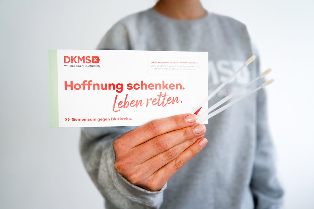 Eine Person hält ein DKMS Registrierungs-Kit Eine Person hält ein DKMS Registrierungs-Kit