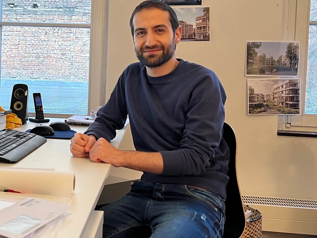 Mann sitzt am Schreibtisch und lächelt in die Kamera Mann sitzt am Schreibtisch und lächelt in die Kamera