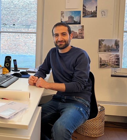 Mann sitzt am Schreibtisch und lächelt in die Kamera Mann sitzt am Schreibtisch und lächelt in die Kamera