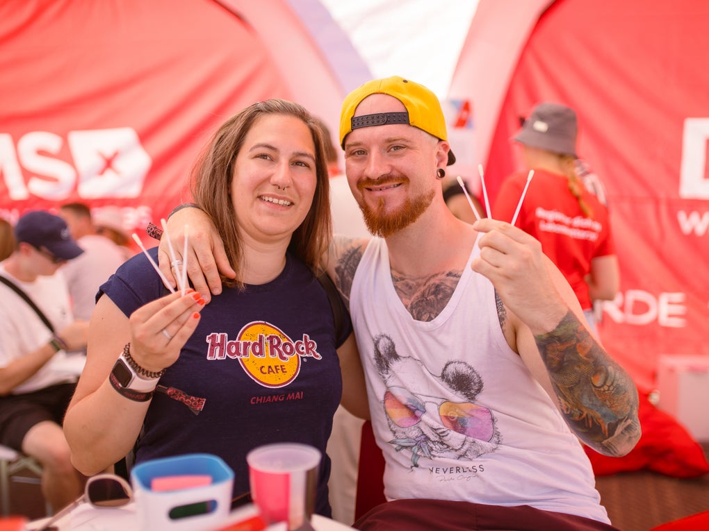 Ein Mann und eine Frau halten Wattestäbchen hoch, im Hintergrund sieht man das DKMS Logo Ein Mann und eine Frau halten Wattestäbchen hoch, im Hintergrund sieht man das DKMS Logo