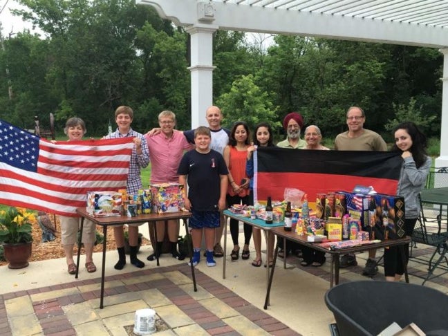 Eine Gruppe von Menschen posiert für ein Foto. Die Personen links halten eine Flagge der Vereinigten Staaten. Die Personen rechts halten eine Deutsche Flagge. Eine Gruppe von Menschen posiert für ein Foto. Die Personen links halten eine Flagge der Vereinigten Staaten. Die Personen rechts halten eine Deutsche Flagge.