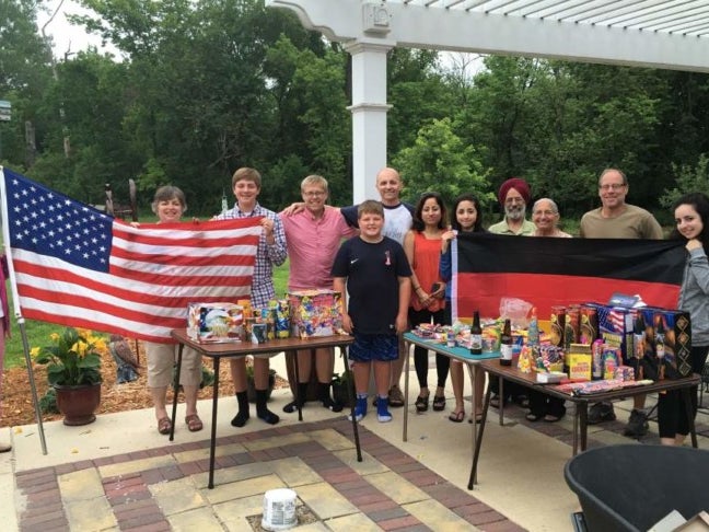 Eine Gruppe von Menschen posiert für ein Foto. Die Personen links halten eine Flagge der Vereinigten Staaten. Die Personen rechts halten eine Deutsche Flagge. Eine Gruppe von Menschen posiert für ein Foto. Die Personen links halten eine Flagge der Vereinigten Staaten. Die Personen rechts halten eine Deutsche Flagge.