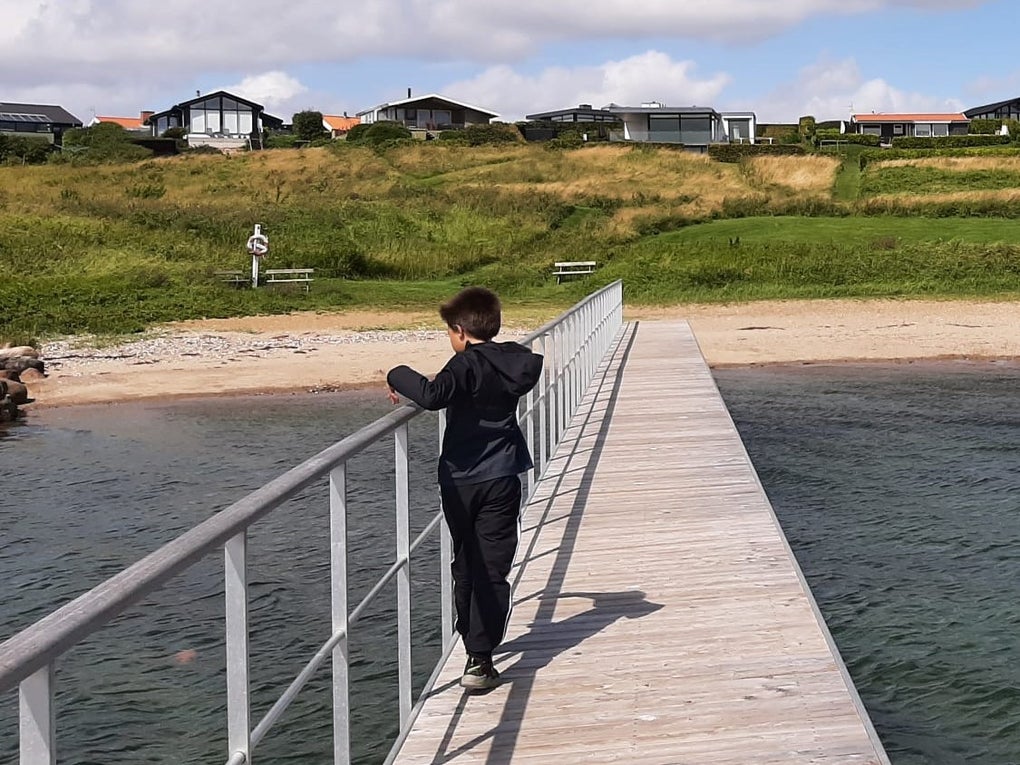 ein Junge steht auf einem Steg der Richtung Strand führt ein Junge steht auf einem Steg der Richtung Strand führt