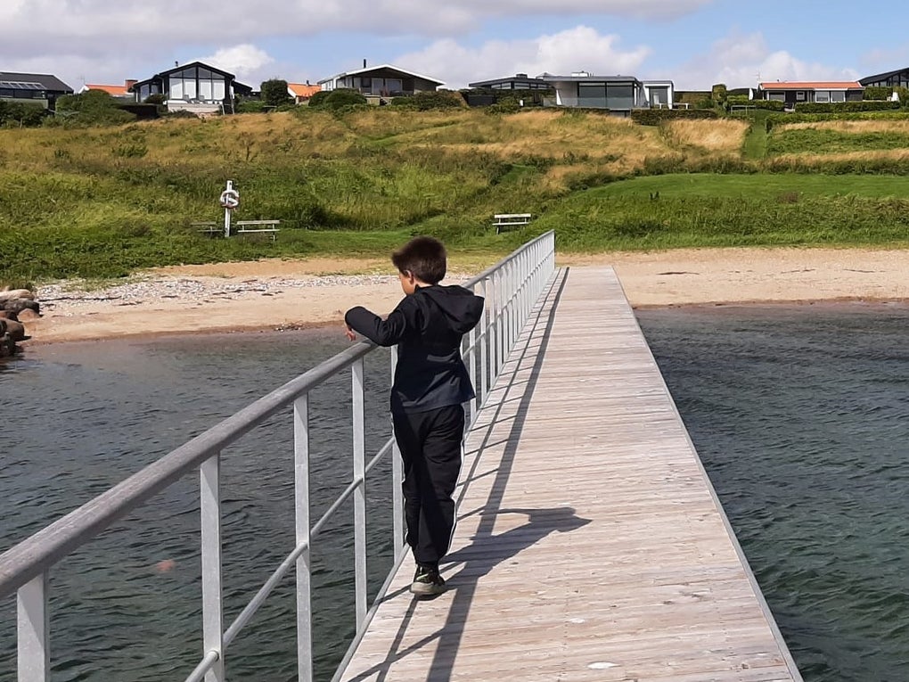 ein Junge steht auf einem Steg der Richtung Strand führt ein Junge steht auf einem Steg der Richtung Strand führt