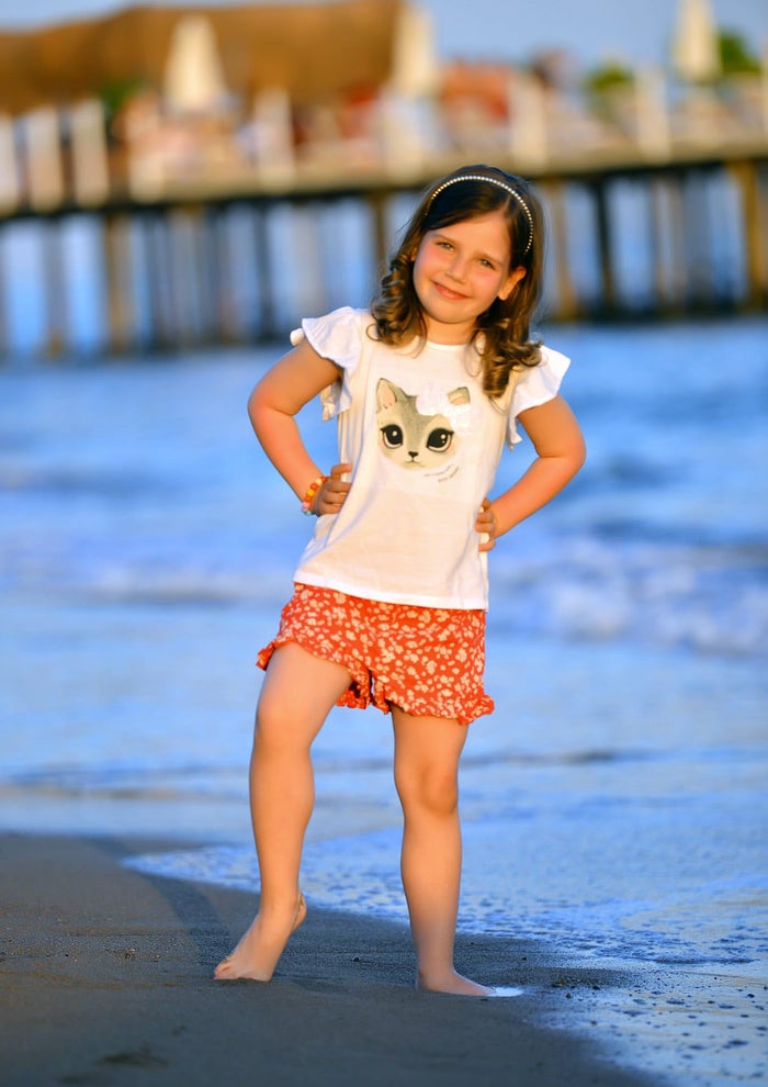 Patientin Mia (5) ist am Strand und lächelt in die Kamera.
