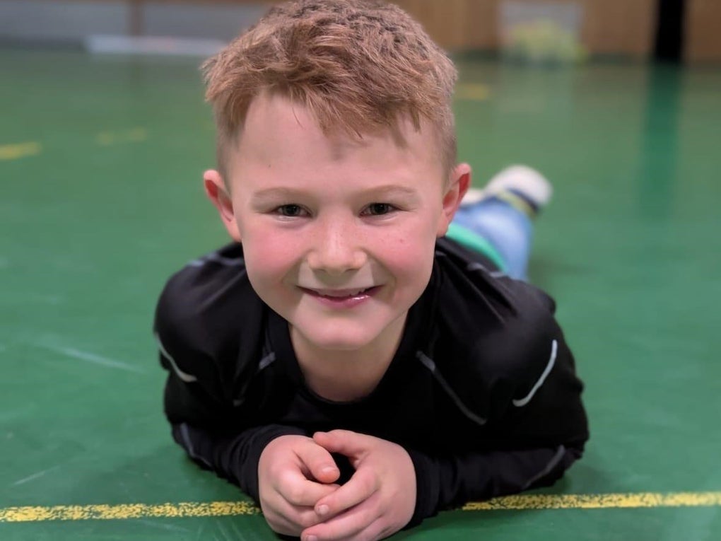 Ein Junge liegt auf dem Bauch auf einem grünen Boden Ein Junge liegt auf dem Bauch auf einem grünen Boden