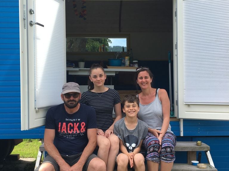 Mattes und seine Familie, die in einer Tür eines blau-weißen Wohnwagens sitzen Mattes und seine Familie, die in einer Tür eines blau-weißen Wohnwagens sitzen