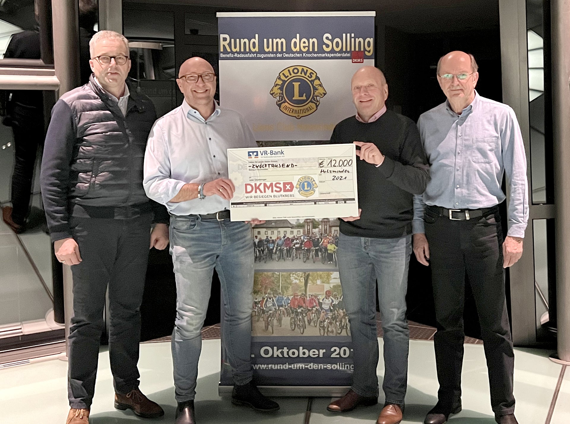 Eine Gruppe von Männern hält einen Scheck Eine Gruppe von Männern hält einen Scheck