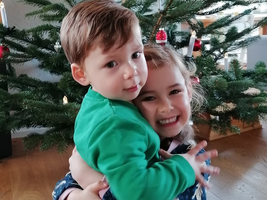 zwei kleine Kinder umarmen sich vor einem Weihnachtsbaum zwei kleine Kinder umarmen sich vor einem Weihnachtsbaum