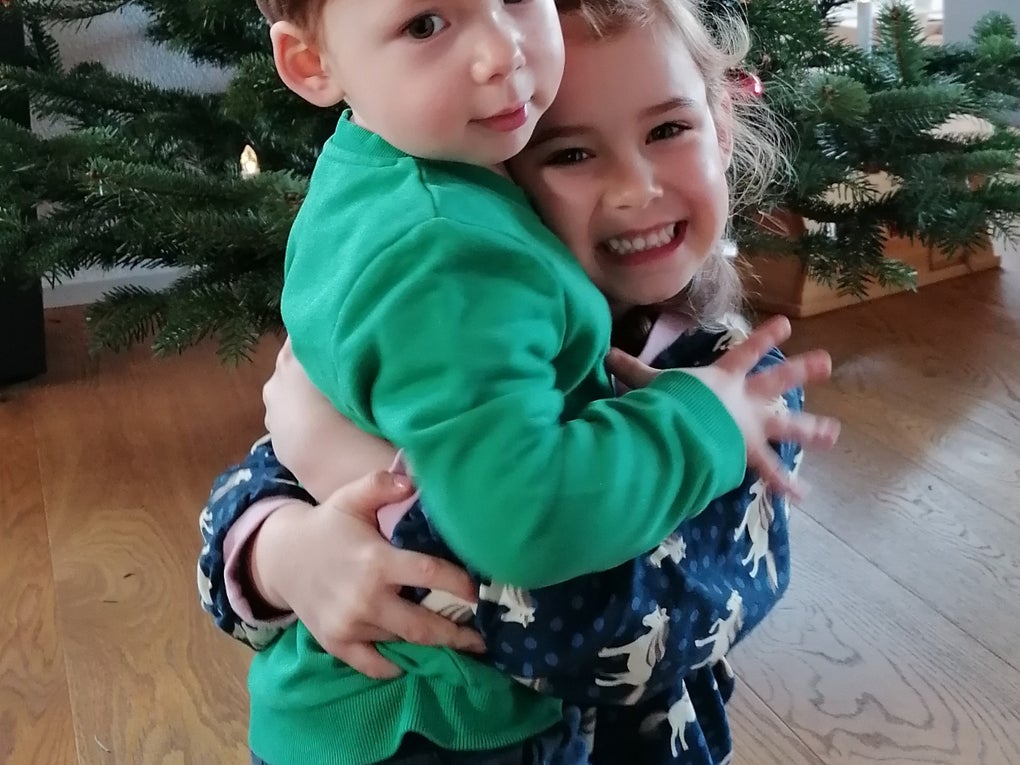 zwei kleine Kinder umarmen sich vor einem Weihnachtsbaum zwei kleine Kinder umarmen sich vor einem Weihnachtsbaum