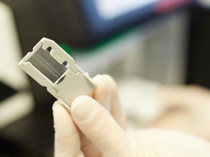 Eine Hand in einem Laborhandschuh, die ein kleines Gerät hält Eine Hand in einem Laborhandschuh, die ein kleines Gerät hält