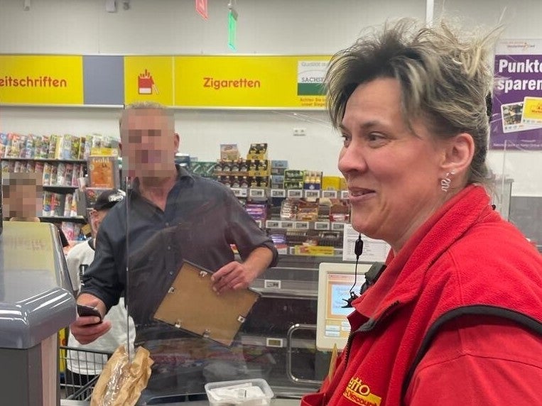 Eine Frau sitzt an einer Supermarktkasse und lächelt. Eine Frau sitzt an einer Supermarktkasse und lächelt.