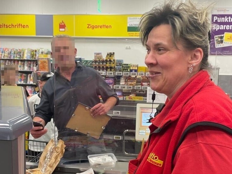 Eine Frau sitzt an einer Supermarktkasse und lächelt. Eine Frau sitzt an einer Supermarktkasse und lächelt.