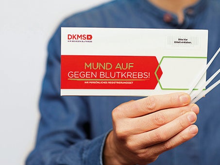 Eine Person hält ein Registrierungskit und Wattestäbchen Eine Person hält ein Registrierungskit und Wattestäbchen
