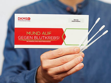 Eine Person hält ein Registrierungskit und Wattestäbchen Eine Person hält ein Registrierungskit und Wattestäbchen