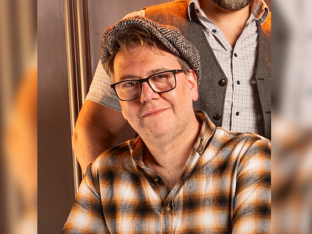 Ein Mann trägt ein kariertes Hemd, Brille und Schiebermütze. Ein Mann trägt ein kariertes Hemd, Brille und Schiebermütze.