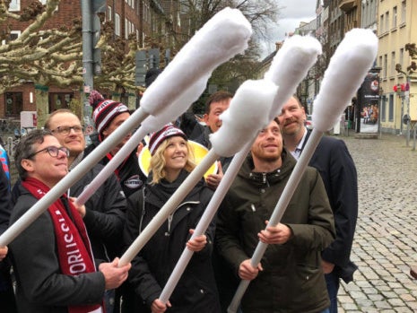 Eine Gruppe von Menschen hält große Wattestäbchen in die Luft Eine Gruppe von Menschen hält große Wattestäbchen in die Luft