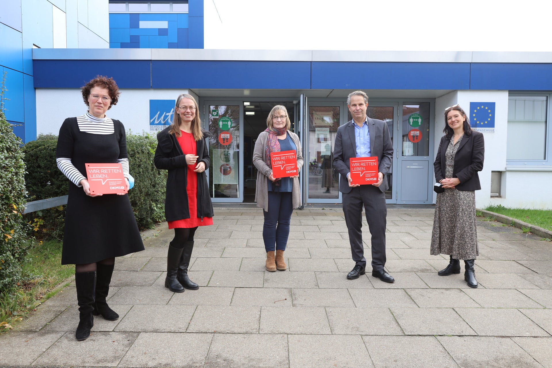 Mehrere Personen halten DKMS Schulsiegel Mehrere Personen halten DKMS Schulsiegel