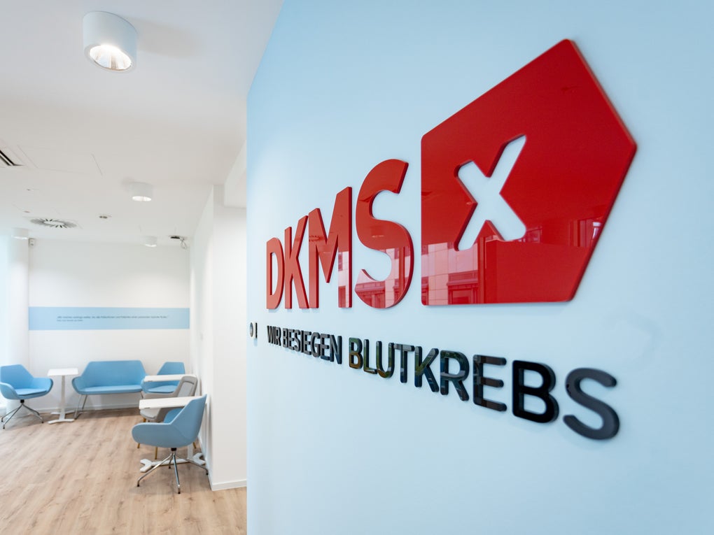 Innenansicht eines DKMS-Büros mit Logo an der Wand und Wartebereich mit Sesseln. Innenansicht eines DKMS-Büros mit Logo an der Wand und Wartebereich mit Sesseln.