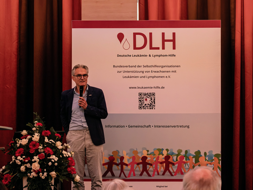 Ein Mann steht auf einer Bühne mit einem Mikrofon. Ein Mann steht auf einer Bühne mit einem Mikrofon.