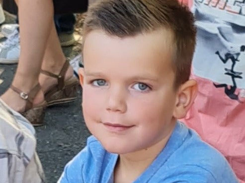 Ein Junge sitzt draußen mit einer Gruppe von Menschen Ein Junge sitzt draußen mit einer Gruppe von Menschen
