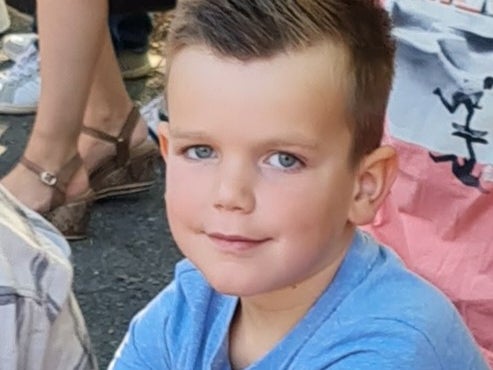 Ein Junge sitzt draußen mit einer Gruppe von Menschen Ein Junge sitzt draußen mit einer Gruppe von Menschen