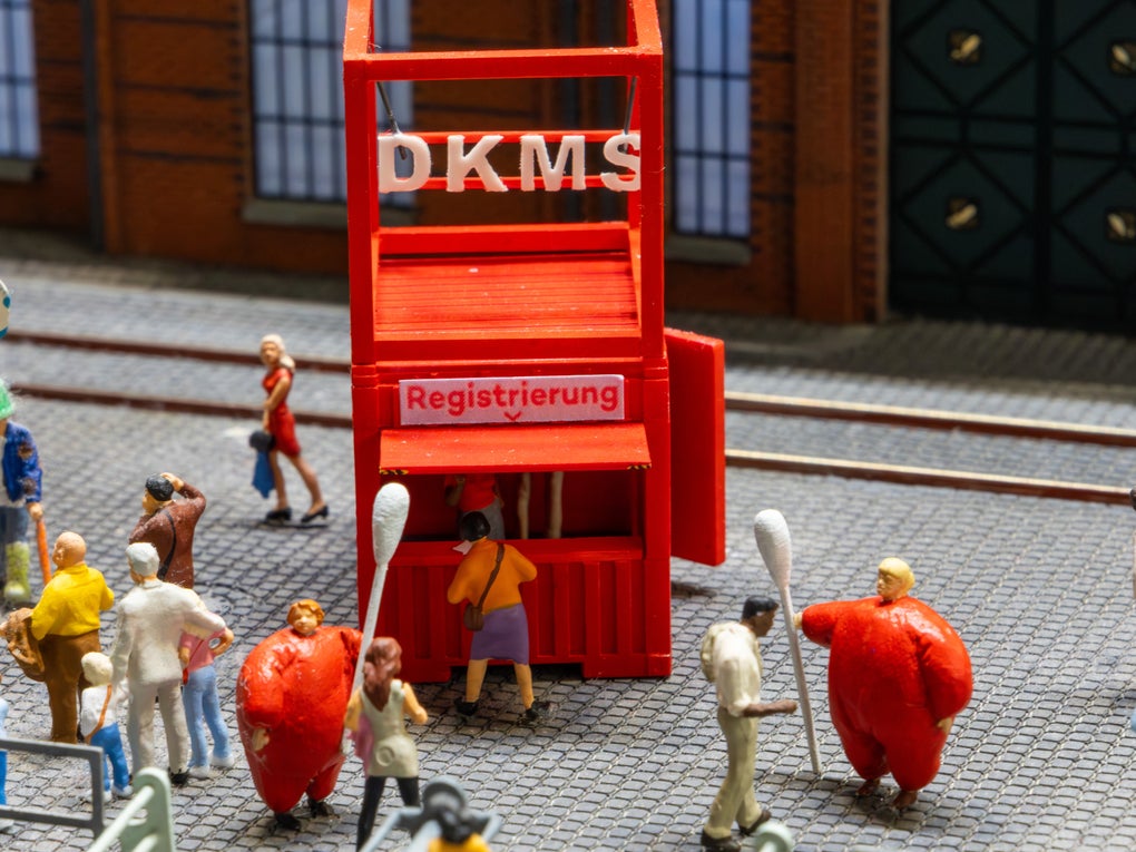 Eine Miniatur einer DKMS Registrierungsaktion. Zwei Figuren in roten Kostümen halten große Wattestäbchen. Eine Miniatur einer DKMS Registrierungsaktion. Zwei Figuren in roten Kostümen halten große Wattestäbchen.