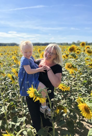 Doreen mit ihrer Enkelin Emma in einem Sonnenblumenfeld.