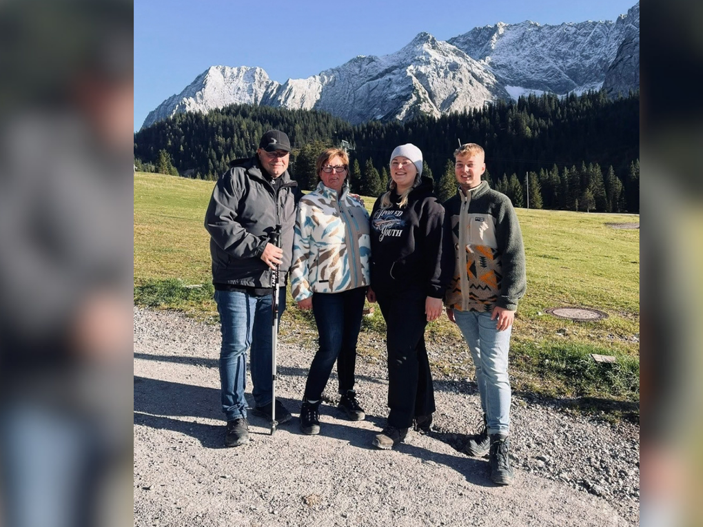 Eine Gruppe von Menschen, die auf einer Schotterstraße steht, im Hintergrund sind Berge zu sehen Eine Gruppe von Menschen, die auf einer Schotterstraße steht, im Hintergrund sind Berge zu sehen