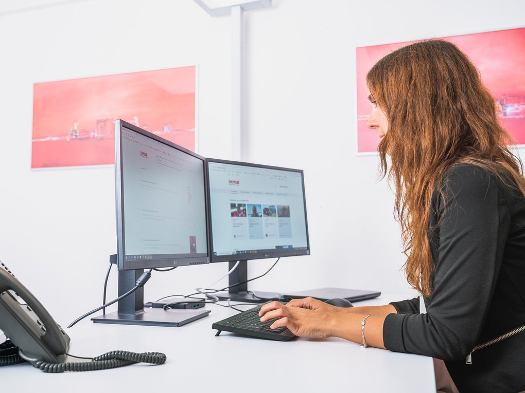 Eine Frau sitzt an einem Schreibtisch und benutzt einen Computer Eine Frau sitzt an einem Schreibtisch und benutzt einen Computer