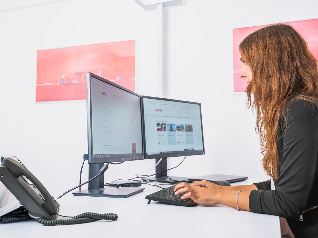Eine Frau sitzt an einem Schreibtisch und benutzt einen Computer Eine Frau sitzt an einem Schreibtisch und benutzt einen Computer