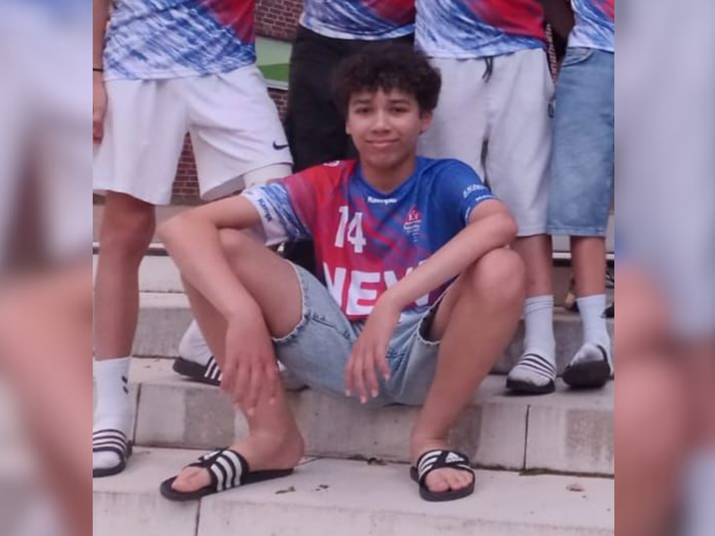 Ein Junge sitzt auf einer Treppenstufe und trägt ein Sportjersey. Ein Junge sitzt auf einer Treppenstufe und trägt ein Sportjersey.