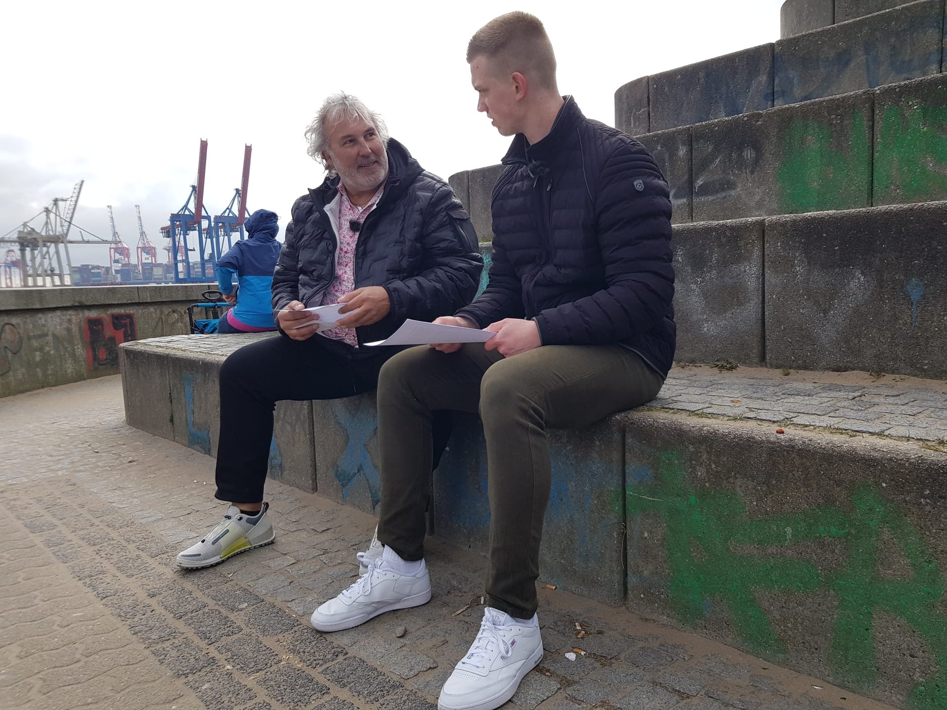 Arno und Nico sitzen auf einer Treppenstufe und unterhalten sich Arno und Nico sitzen auf einer Treppenstufe und unterhalten sich